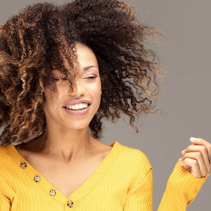COILBAR Textured Haircare: woman wearing yellow shirt with wind blowing through type 4 curls